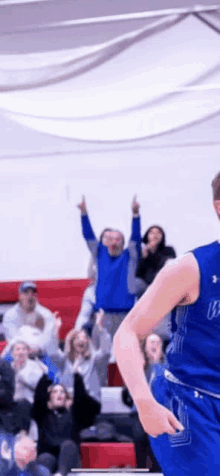 a basketball player is standing in front of a crowd of people .