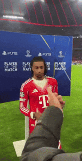 a man in a t-mobile jersey stands in front of a player of the match banner