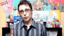 a man wearing glasses stands in front of a display of children 's books including one titled la bande a picsou