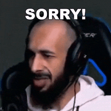 a bald man with a beard is wearing headphones and making a sorry gesture .