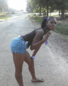 a woman in shorts is posing for a picture on the side of a road