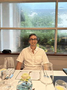 a man sits at a table in front of a window with a menu on it