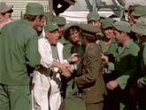 a group of soldiers are shaking hands with each other in a field .