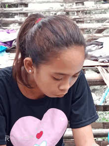 a girl in a black shirt with a pink heart on it