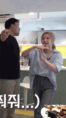 a man and a woman are standing next to each other in a kitchen with chinese writing on the wall behind them