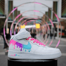 a pair of white nike shoes with pink laces and a drip design