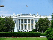 the white house with a fountain in front of it and a flag on top of it .