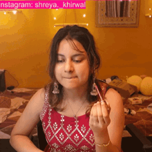 a woman in a red dress is making a funny face in front of a yellow wall with the words instagram shreya khirwal on it