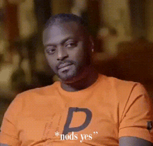 a man wearing an orange t-shirt with the letter d on it .
