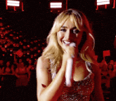 a woman is singing into a microphone in front of a crowd