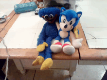 a blue stuffed animal sitting next to a sonic stuffed animal on a counter top