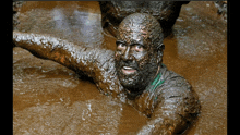 a man covered in mud is swimming in a muddy pool