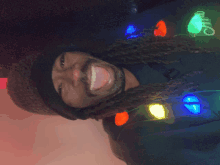 a man with dreadlocks wearing a hat and christmas lights around his neck with the letter c on it