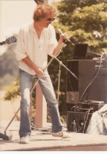 a man is singing into a microphone while standing on a stage