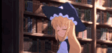 a girl in a witch hat stands in front of a bookshelf