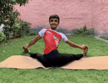 a young man sitting on a yoga mat with a red shirt that says ' sdm ' on the back