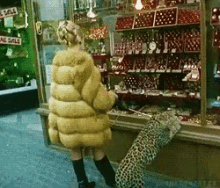 a woman in a fur coat is standing next to a leopard in front of a store that has a sign that says no sale