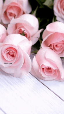 a bunch of pink roses on a white wooden surface