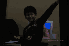 a boy wearing a shirt that says forced ide is standing in front of a computer monitor