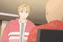 a man in a pink hoodie is talking to a bald man in a red shirt
