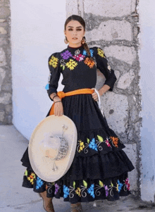 a woman in a black dress holds a sombrero in her hand