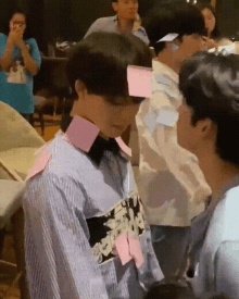 a group of people are standing around each other with sticky notes on their shirts .