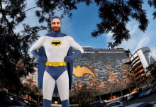 a man in a batman costume stands in front of a building that says bienvenidos