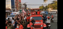 a crowd of people are gathered around a red jeep that says team on the front .