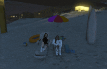 a couple sits under an umbrella on a beach at night