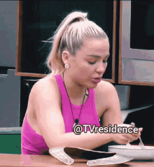 a woman in a pink tank top is sitting at a table with a bowl of food and a caption that says tvresidence