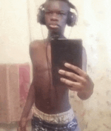 a young man wearing headphones is taking a selfie with his cell phone .