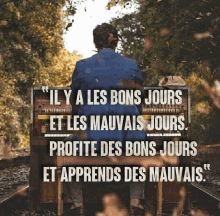 a man is sitting on a suitcase with a quote in french