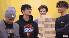 a group of young men standing around a stack of wooden blocks with pop buzz meets written on the bottom