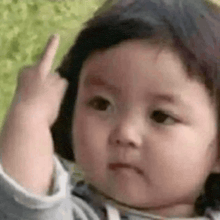 a baby is making a funny face and giving the middle finger .