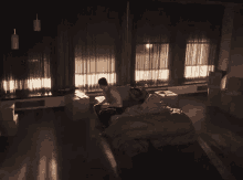 a man is sitting on a couch next to a bed in a dark room .