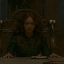 a woman in a green dress sits at a table with a plate of food in front of her