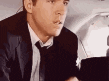 a man in a suit and tie is sitting in the back of an airplane .