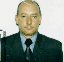 a man in a suit and tie is standing in front of a white background .