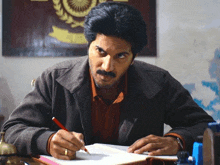 a man is sitting at a desk writing on a piece of paper .