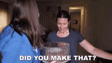 a woman is holding a cake in front of another woman who is asking her if she made it .