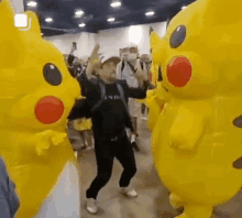 a man is dancing with two pikachu mascots in a room .