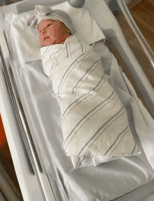 a newborn baby is wrapped in a striped blanket and wearing a hat