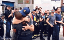 a group of firefighters are hugging in front of a crowd .