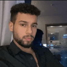 a man with a beard and curly hair is taking a selfie in a room .