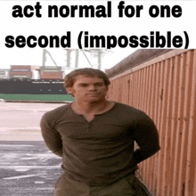 a man standing in front of a fence with the words act normal for one second ( impossible ) on the top