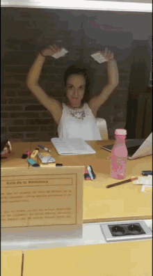 a woman sitting at a desk with her arms in the air behind a sign that says zone de la bibliotheque