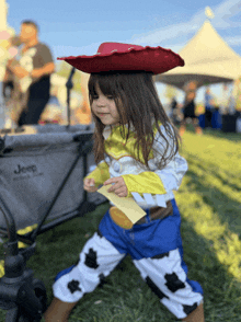 a little girl dressed as jessie from toy story stands in front of a jeep stroller