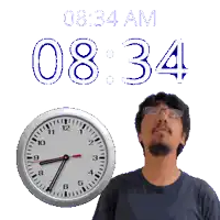 a man with glasses stands in front of a clock that says 8:34 am