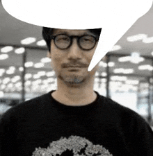 a man wearing glasses and a black shirt with a speech bubble over his head .