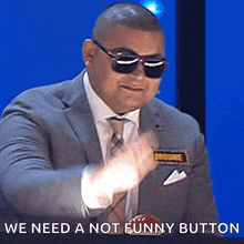 a man wearing sunglasses and a suit has the words we need a not funny button below him